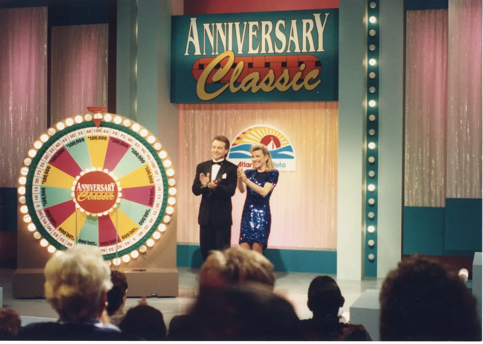 Vanna White and a host on the set of the Anniversary Classic broadcast beside a prize wheel