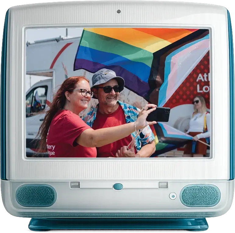 A vintage desktop computer displaying a photo of two Atlantic Lottery employees taking a selfie at a Pride celebration