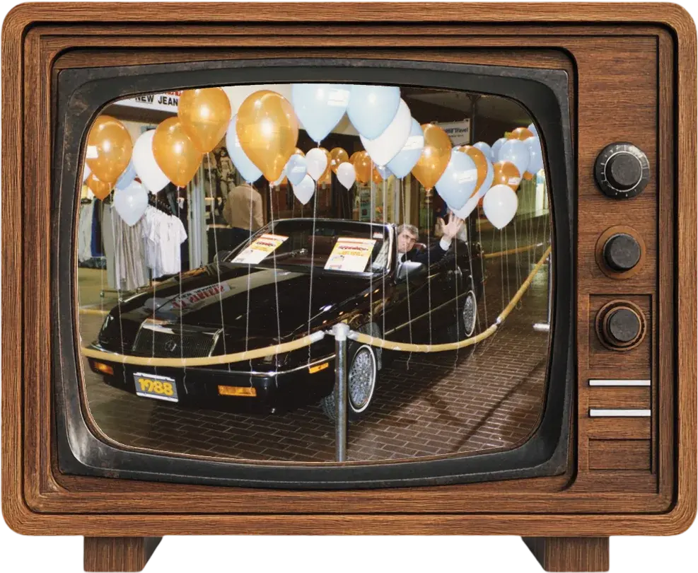 A vintage television showing a 1988 prize car surrounded by balloons at a mall promotion