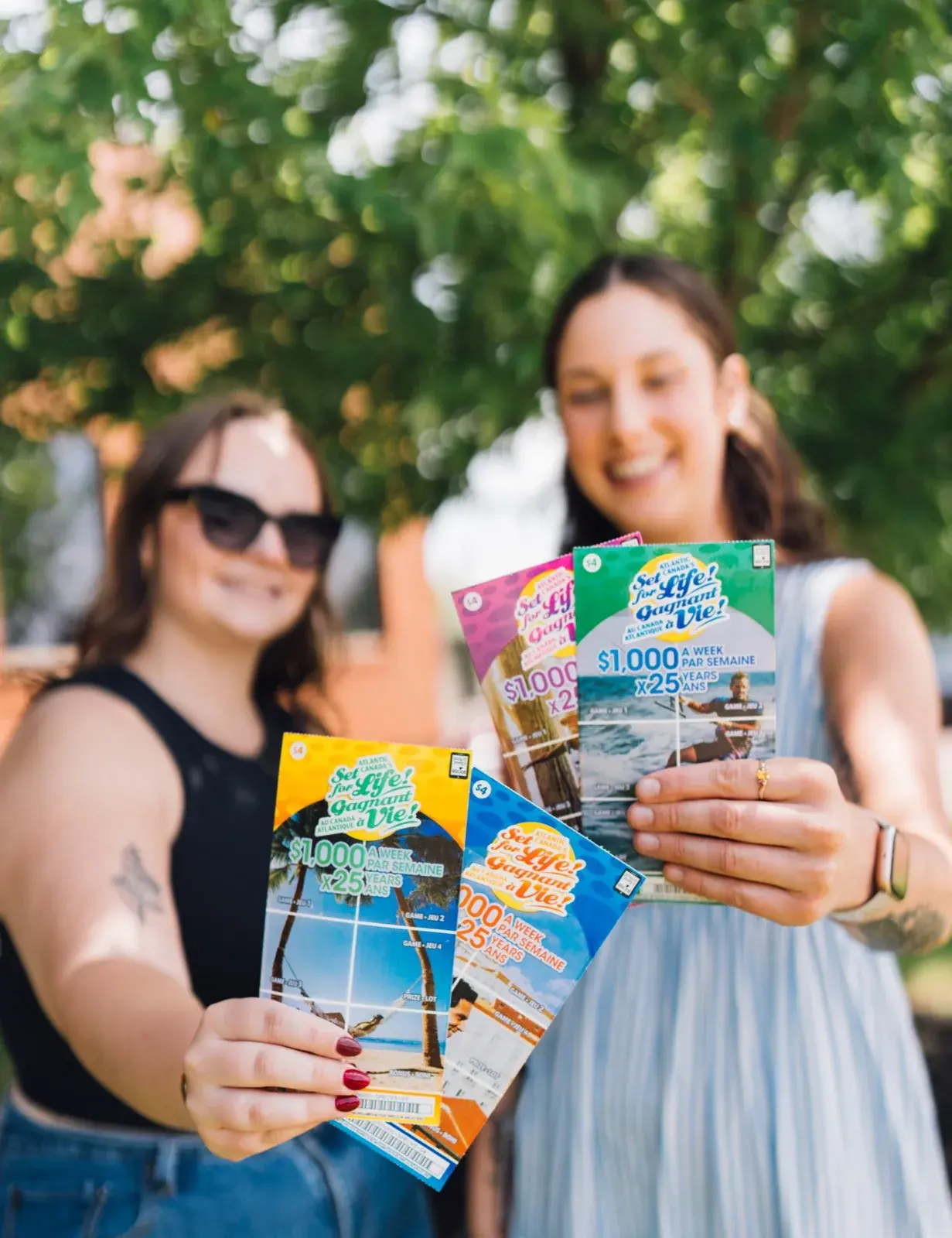 Two smiling women holding up Set for Life scratch tickets